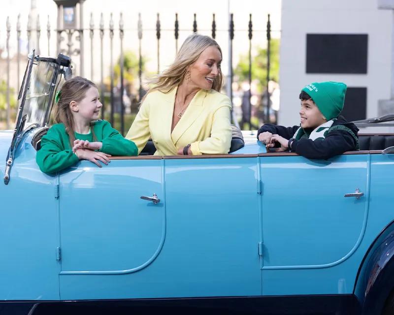 Woman and two childern getting driven in an old car